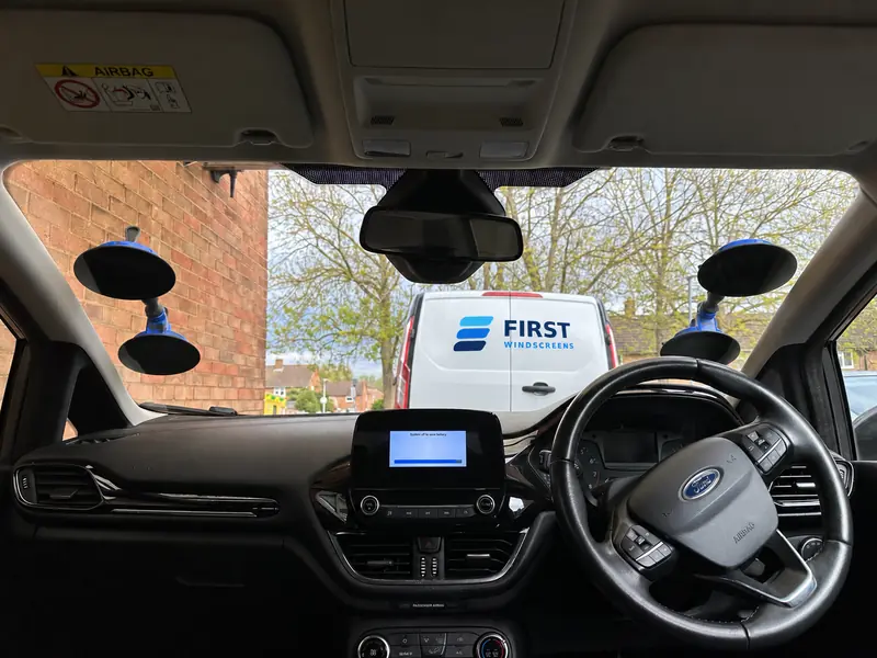 View through a windscreen with fitting equipment and a white First Windscreens service van outside